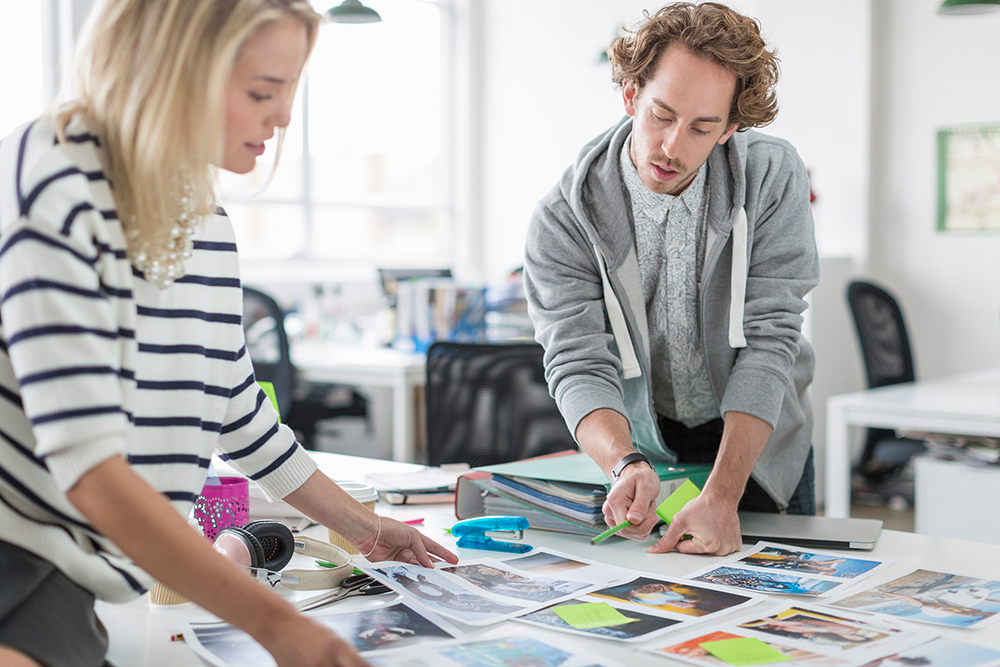 young colleagues discussing photographs in meeting 1000